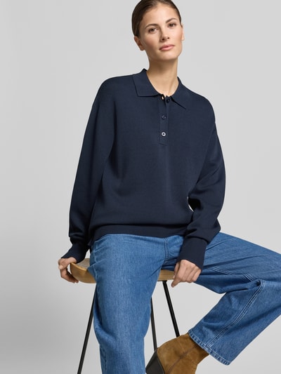 Frauenmodel trägt dunkelblaues Strick-Polohemd im Wide Fit von SIC curated by Tinvcb mit Polo-Kragen und elastischen Ärmelabschlüssen, Ganzkörperansicht von vorne.