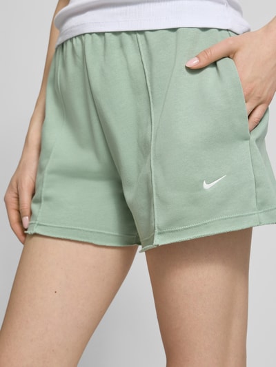 Frauenmodel trägt Regular Fit Shorts mit Tunnelzug von Nike aus Baumwoll-Mix mit Logo-Stitching in Mintgrün, Nahaufnahme Oberschenkel.