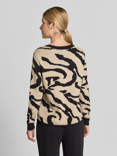 Frauenmodel trägt Strickpullover aus Viskose-Mix Modell 'TIF' von VILA im Allover-Look, Beige mit schwarzen Mustern, Ganzkörperansicht Rückansicht.