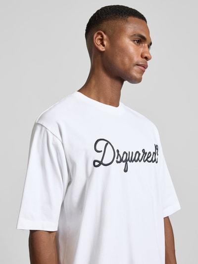 Männermodel trägt Loose Fit T-Shirt aus reiner Baumwolle von Dsquared2 in Weiß mit Label-Stitching, Nahaufnahme Oberkörper.