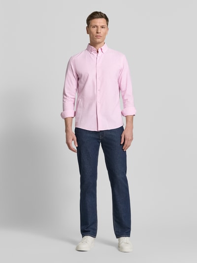 Męski model nosi Slim Fit Freizeithemd aus reiner Baumwolle von MCNEAL w jasnoróżowym kolorze, długie rękawy, krój slim fit, bawełna, kołnierzyk button-down, zaokrąglony dół, długość tyłu w rozmiarze M: 74 cm, szerokość ramion w rozmiarze M: 44 cm, długość rękawa w rozmiarze M: 65 cm, widok całej sylwetki z przodu.