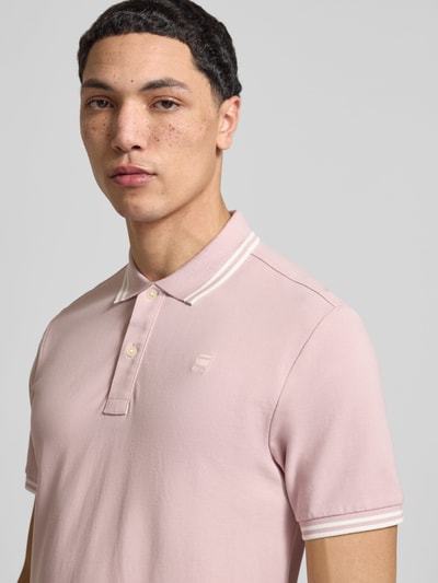 Mannenmodel draagt Slim Fit Poloshirt met Logo-Stitching Model 'Dunda' van G-Star Raw van katoenmix in lichtroze, Nahaufnahme Oberkörper.