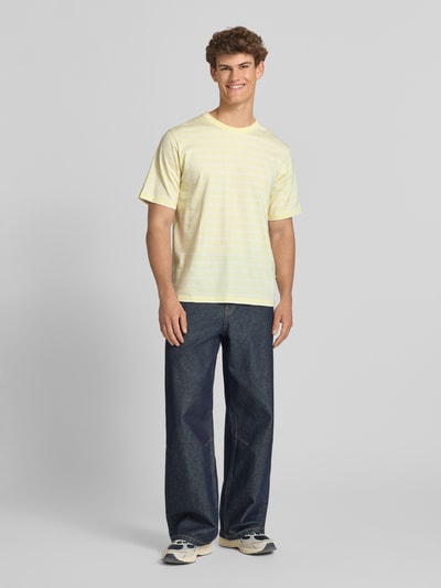 Männermodel trägt T-Shirt mit Streifenmuster und Label-Stitching von Jack & Jones, Reine Baumwolle, Relaxed-Fit, Rundhalsausschnitt, Ganzkörperansicht von vorne.