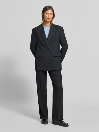 Frauenmodel trägt Relaxed Fit Blazer mit Viskose-Anteil von MYON, Schwarz, Reverskragen, doppelte Knopfleiste, Ganzkörperansicht von vorne.