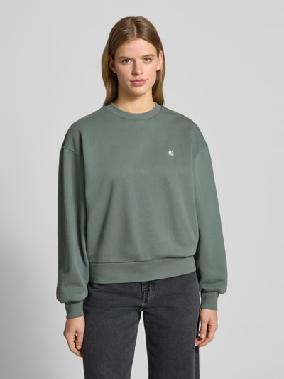 Frauenmodel trägt Sweatshirt mit Label-Stitching Modell 'CASEY' von Carhartt Work In Progress in Grün, Reine Baumwolle, Relaxed-Fit, Rundhalsausschnitt, Ganzkörperansicht von vorne.