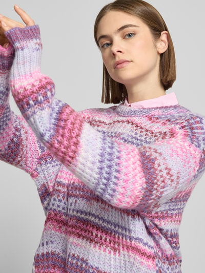 Frauenmodel trägt Regular Fit Pullover in Strick-Optik Modell 'Simone' von JJXX in Rosa- und Lilatönen, Nahaufnahme Oberkörper, Rundhalsausschnitt, elastische Abschlüsse, Rückenlänge 60 cm, Ärmellänge 68 cm.