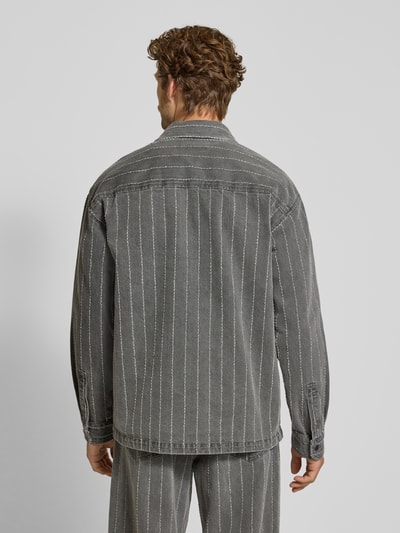 Männermodel trägt Regular Fit Hemdjacke aus reiner Baumwolle Modell 'David' von Wood Wood in grauer Denim-Optik mit weißen Streifen, Ganzkörperansicht Rückansicht.