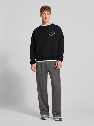 Męski model nosi Relaxed Fit Strickpullover aus reiner Baumwolle von PROHIBITED z bawełny, krój relaxed fit, wyhaftowane logo, prążkowane wykończenia, długość tyłu w rozmiarze M: 64 cm, długość rękawów w rozmiarze M: 59 cm, widok całej sylwetki z przodu