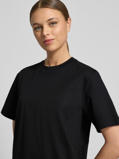 Vrouwenmodel draagt Relaxed Fit T-Shirt uit zuivere katoen model 'EHARPA' van BOSS, effen zwart, ronde hals, korte mouwen, label stitching, detailopname bovenlichaam.