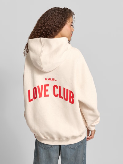 Frauenmodel trägt Hoodie mit Statement-Print Modell 'Love Club' von Karo Kauer aus Reine Baumwolle im Oversized-Fit, Ganzkörperansicht Rückansicht.