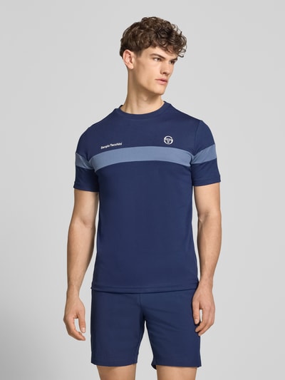 Männermodel trägt Regular Fit T-Shirt mit Logo-Print Modell 'Leone' von SERGIO TACCHINI in Dunkelblau, Rundhalsausschnitt, Ganzkörperansicht von vorne.