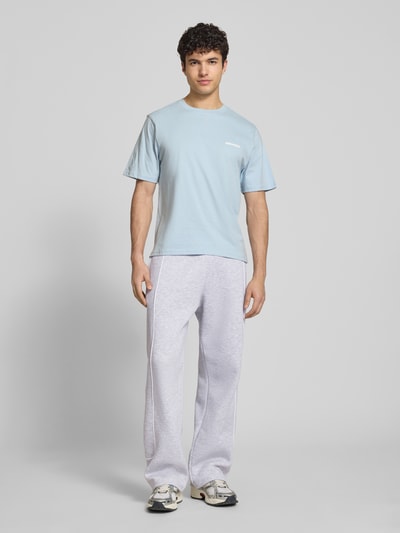 Männermodel trägt Sweatpants mit elastischem Bund und Logo von REVIEW aus reiner Baumwolle im Relaxed-Fit, Ganzkörperansicht von vorne.
