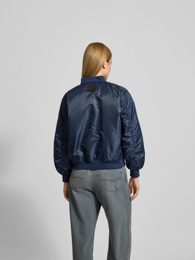 Frauenmodel trägt Bomberjacke mit Reißverschluss von Anine Bing in Dunkelblau mit Gerippte-Abschlüsse, Stehkragen, Pattentaschen, Lockerer-Schnitt, Rückenlänge 59 cm, Brustweite 63 cm, Ärmellänge 61 cm, Ganzkörperansicht Rückansicht.