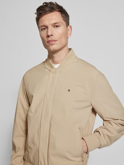 Männermodel trägt Regular Fit Blouson mit wasserabweisender Funktion von Tommy Hilfiger in Beige, College-Kragen, Nahaufnahme Oberkörper.