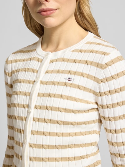 Frauenmodel trägt Strickjacke mit Baumwoll-Anteil von Gant, Zopfmuster, Rundhalsausschnitt, Knopfleiste, Nahaufnahme Oberkörper.