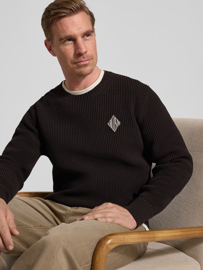 Männermodel draagt Regular Fit Pullover aus katoenmix Model 'COTES PERLES' van Lacoste in effen zwart, logopatch, ribtricottextuur. Nahaufnahme bovenlichaam.