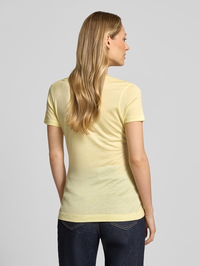 Frauenmodel trägt Slim Fit T-Shirt aus reinem Lyocell von Guess in Gelb mit Logo-Stitching und Rückenlänge 58 cm, Ganzkörperansicht Rückansicht.