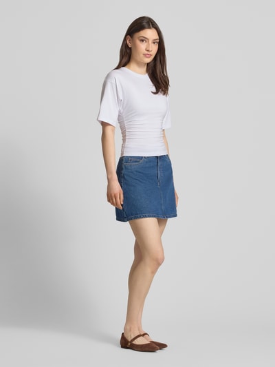 Frauenmodel trägt T-Shirt in tailliertem Schnitt Modell 'ELORA' von JJXX, weiß, Baumwoll-Mix mit Modal, Rundhals, Ganzkörperansicht von vorne.