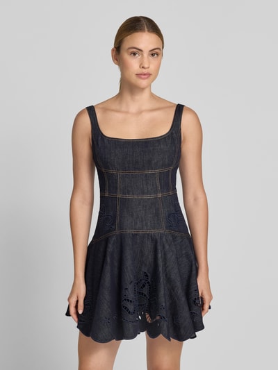 Frauenmodel trägt Minikleid in Denim-Optik von Self-Portrait aus elastischem Baumwoll-Mix, taillierte Passform, Loch-Stickereien, Ärmelloses-Design, dunkelblaue Farbtöne, sichtbare Nähte, strukturierte Textur, Ganzkörperansicht von vorne.