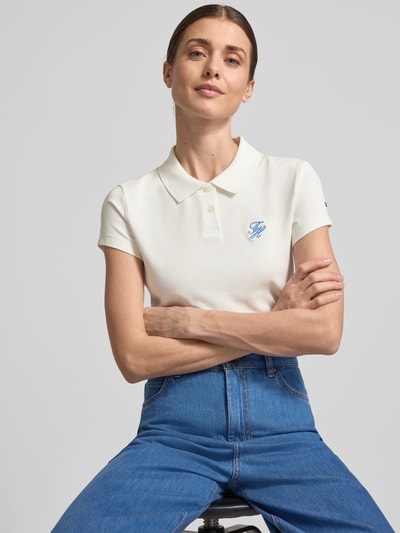 Frauenmodel trägt Slim Fit Poloshirt aus Baumwoll-Mix von Tommy Hilfiger in Unifarbe mit Polokragen und Logo-Stitching, Nahaufnahme Oberkörper.