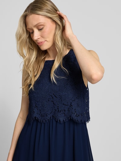 Frauenmodel trägt Maxikleid mit rückseitigem Schlüsselloch-Ausschnitt von Vila aus dunkelblauem Baumwoll-Mix mit Spitze, Nahaufnahme Oberkörper.