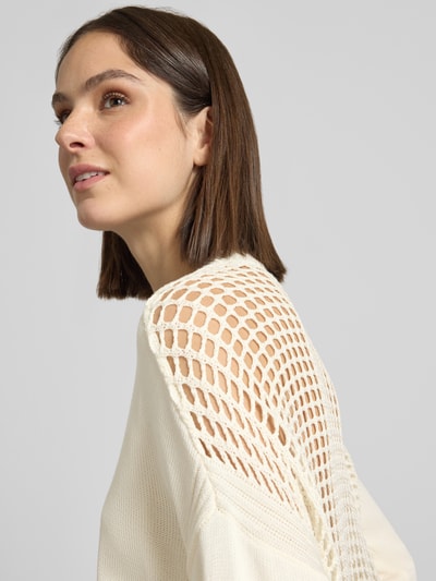 Frauenmodel trägt Strickpullover mit V-Ausschnitt von ARMANI EXCHANGE in Creme, aus reiner Baumwolle, Strukturstrick, Nahaufnahme Oberkörper.