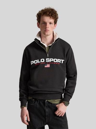 Männermodel trägt Relaxed Fit Troyer aus Baumwoll-Mix von Polo Ralph Lauren in Schwarz mit weißer Schrift, Ganzkörperansicht von vorne.