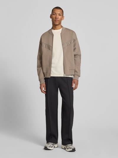 Männermodel trägt Oversized Sweatjacke aus Baumwoll-Mix Modell 'DROMZIP' von HUGO in Beige, glatte Struktur, College-Kragen, Ganzkörperansicht von vorne.