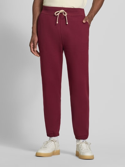 Männermodel trägt Relaxed Fit Sweathose aus Baumwoll-Mix von Polo Ralph Lauren, weinrot mit Kordelzug, Ganzkörperansicht von vorne.