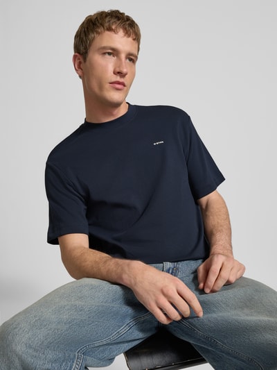 Męski model nosi Regular Fit T-Shirt mit Logo-Print Modell 'True' von G-Star Raw, krój regular fit, okrągły dekolt, długość tyłu w rozmiarze M: 66 cm, granatowy, gładka faktura, widok z przodu, ujęcie do pasa