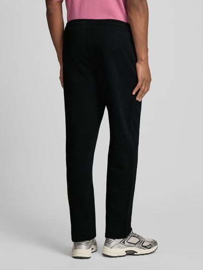 Mannenmodel draagt Sweatpants mit elastischem Bund und Logo van GAP, zwarte katoenmix, regular fit, elastische tailleband, logo, volledige lichaamsachteraanzicht.