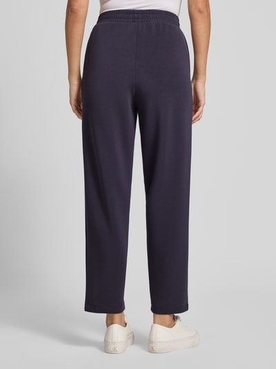 Frauenmodel trägt Sweatpants mit elastischem Bund und Längsnähten von Jake*s Casual, Modal-Mix mit Stretch-Anteil, Barrel Fit, dunkelblau, weiche Textur, Ganzkörperansicht Rückansicht.