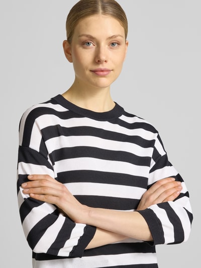 Frauenmodel trägt Regular Fit Oberteil aus Viskose-Mix Modell 'Lani' von GUIDO MARIA KRETSCHMER WOMAN, schwarz-weiße Streifen, Strick-Optik, 3/4-Arm, Rundhalsausschnitt, elastische Ärmelabschlüsse, Nahaufnahme Oberkörper.