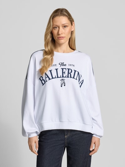 Frauenmodel trägt Oversized Sweatshirt aus Baumwoll-Mix Modell 'JAMIE' von Vero Moda, weiß, blauer Print, Kontraststreifen, Nahaufnahme Oberkörper.