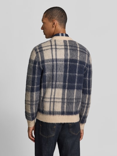 Männermodel trägt Pullover aus Wolle mit V-Ausschnitt von BARBOUR, mehrfarbig kariert, Strickoptik, Ganzkörperansicht Rückansicht.