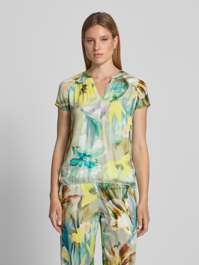 Frauenmodel trägt Regular Fit Bluse aus Viskose im Allover-Look von Betty Barclay in bunten Gelb- und Grüntönen, Ganzkörperansicht von vorne. Rückenlänge 61 cm, Ärmellänge 13 cm, V-Ausschnitt, Damen Bluse, Reine Viskose.