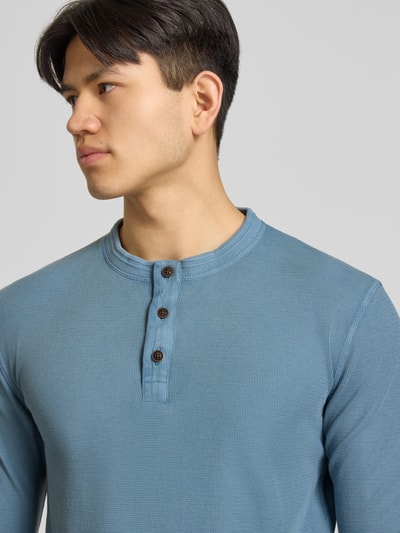 Męski model nosi Longsleeeve mit Knopfleiste od Superdry z bawełny, krój regular fit, okrągły dekolt, listwa guzikowa, niebieski, zbliżenie na górę ciała