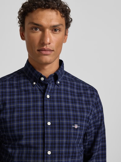 Męski model nosi Koszulę casualową z listwą guzikową marki Gant z bawełny, krój regular fit, kołnierzyk typu button down, niebieska krata, wyhaftowane logo na piersi, długość tyłu 76 cm, szerokość ramion 56 cm, długość rękawów 65 cm, widok z przodu, zbliżenie na górną część ciała.