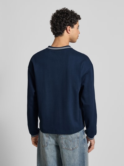 Männermodel trägt Strickpolo aus reine katoen Modell 'JORNIAGARA' van Jack & Jones, loose fit, donkerblauw, achteraanzicht, ganzkörperansicht rückansicht.