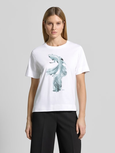 Frauenmodel trägt Regular Fit T-Shirt aus reiner Baumwolle Modell 'ELPHA' von BOSS mit Motiv-Print, Rundhals und Kurzarm, Ganzkörperansicht von vorne.