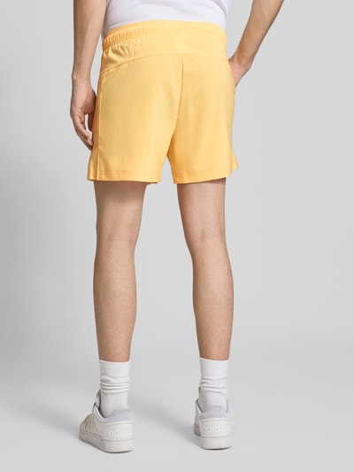 Męski model nosi Regular Fit Sport-Shorts mit Label Print od adidas Training, efekt: jednolity kolor, krój regular fit, nadruk z logo, elastyczny ściągacz z tunelem, kieszenie zapinane na zamek błyskawiczny, Ganzkörperansicht Rückansicht.