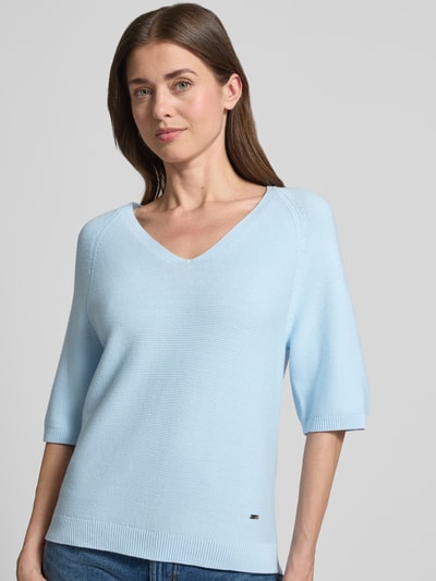 Frauenmodel trägt Regular Fit Strickpullover aus Baumwoll-Mix von s.Oliver RED LABEL, Optik: Unifarben, Kurzarm, V-Ausschnitt, Logo-Applikation aus Metall, Label-Applikation aus Metall, Materialverarbeitung: Strick, Material: Baumwoll-Mix, sanft blaue Farbe, glatte Struktur, Ganzkörperansicht von vorne.