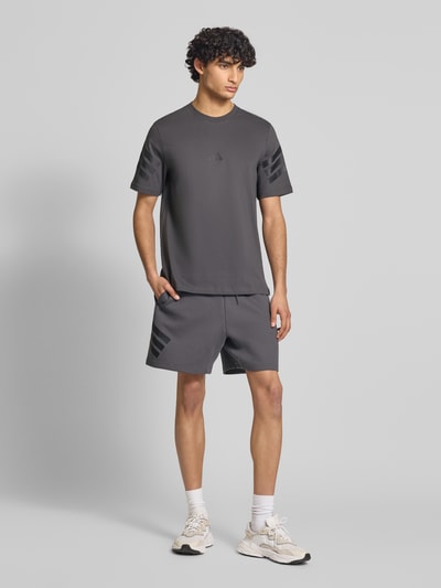 Männermodel trägt Regular Fit Sweatshorts mit Baumwoll-Anteil von adidas Sportswear, Optik: Unifarben, Passform: Regular-Fit, Logo-Print, Bundabschluss: elastisch mit Tunnelzug, seitliche Eingrifftaschen, Materialverarbeitung: Sweat, Ganzkörperansicht von vorne.