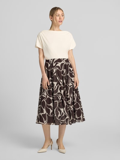 Frauenmodel trägt Cocktailkleid im 2-in-1-Look mit Drapierungen von Christian Berg Cocktail, A-Linie, Midikleid, abstraktes Muster, Farben Creme und Dunkelbraun, Rückenlänge bei Größe 36: 116 cm, Brustweite bei Größe 36: 45 cm, Ganzkörperansicht von vorne.