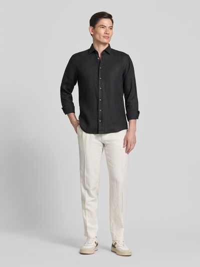 Męski model nosi Regular Fit Business-Hemd aus Leinen mit Kentkragen od SEIDENSTICKER, czarny, krój regular fit, len, guzik, widok całej sylwetki z przodu, długość tyłu 79 cm, szerokość w rozmiarze 40: 46 cm, długość rękawa 67 cm.