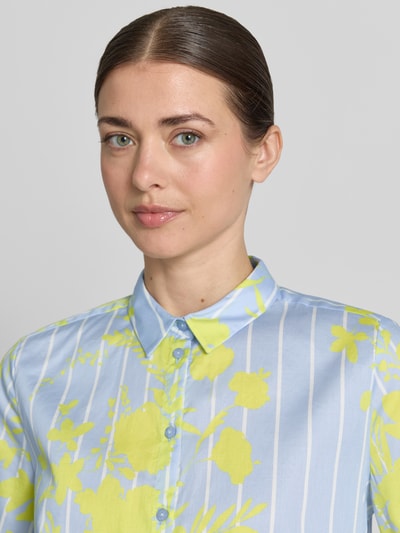 Vrouwenmodel draagt Bluse mit Hemdblusenkragen und Knopfleiste van Milano Italy, lichtblauw met witte strepen en gele bloemen, pure katoen, regular fit, hemdblousekraag, knoopsluiting, detailopname bovenlichaam.