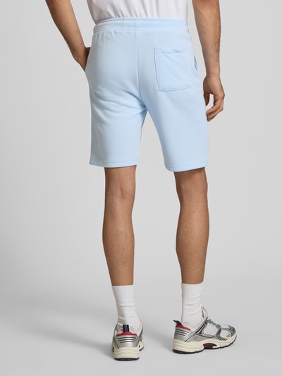 Męski model nosi Sweatshorts mit elastischem Bund Modell 'KARLOS' od Blend, bawełniany miks, krój regular fit, szorty w kolorze jasnoniebieskim, elastyczny pas z troczkiem, szerokość w rozmiarze M: 42 cm, długość nogawki od wewnątrz: 21 cm, widok całej sylwetki z tyłu.