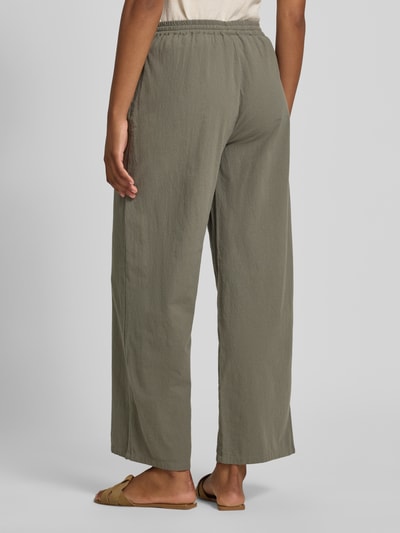 Frauenmodel trägt Stoffhose in verkürzter Passform Modell 'CISSIE' von Soyaconcept aus Reine Baumwolle, Wide-Leg-Pants, elastischer Bund mit Tunnelzug, Bundweite für Größe S 37 cm, Innenbeinlänge 73 cm, olivegrüne Farbe, strukturierte Oberfläche, Ganzkörperansicht Rückansicht.
