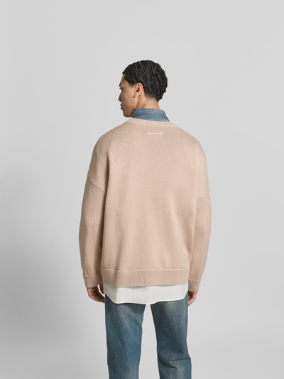 Männermodel trägt Oversized Pullover aus Woll-Mix von MM6 Maison Margiela in Beige mit Strick-Optik, Rückenansicht, Ganzkörperansicht Rückansicht.