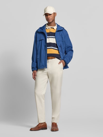 Mannenmodel draagt Regular Fit regenjack met logo-stitching van Polo Ralph Lauren, look: effen, regular fit, capuchon met tunnelkoord, tweewegritssluiting, gestikt logo, lange mouw, elastisch aan de mouw en rompzoom, zij-steekzakken, geheelopname vooraanzicht.